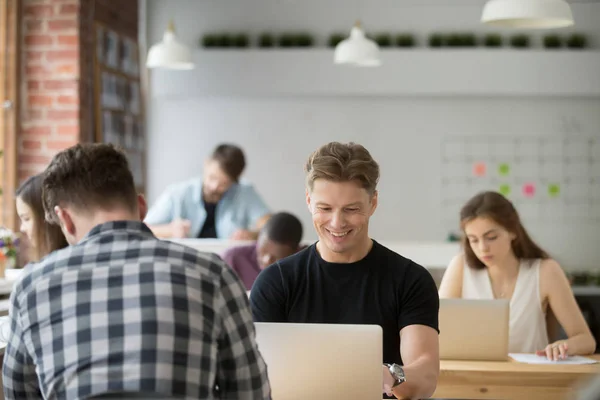 Усміхнений бізнесмен дивиться на екран ноутбука в загальному офісі . — стокове фото