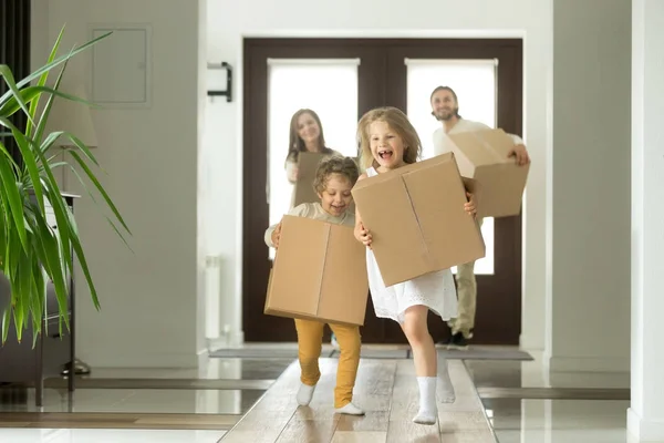 Niños emocionados corriendo cajas de espera, familia mudándose en casa nueva — Foto de Stock