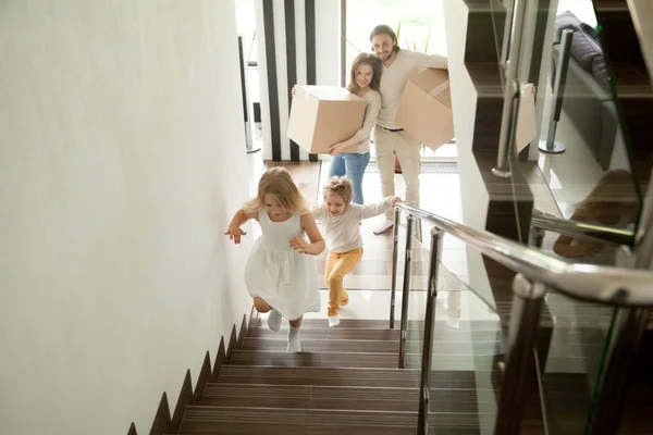 Happy children going upstairs, family with boxes moving in house — Stock Photo, Image