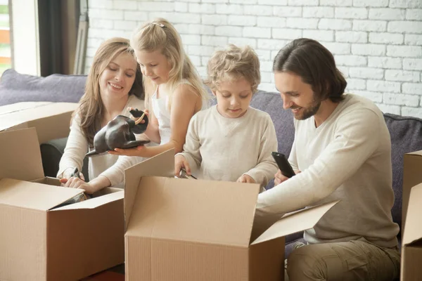 Familia feliz con niños desempacando cajas que se mueven en un nuevo hogar — Foto de Stock