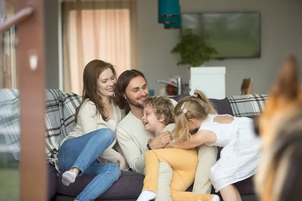 Familia feliz con perro divirtiéndose en el sofá en casa — Foto de Stock