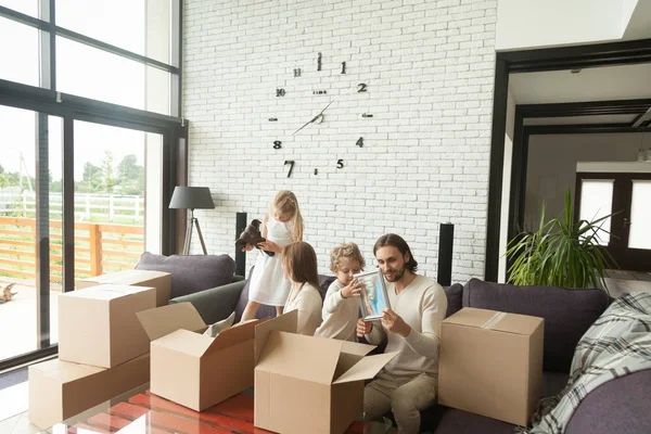 Joven familia feliz con niños desempacando cajas en la sala de estar — Foto de Stock