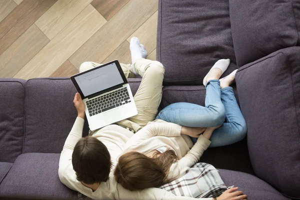 Unga paret sitter på soffan embracing ovanifrån hålla laptop, — Stockfoto