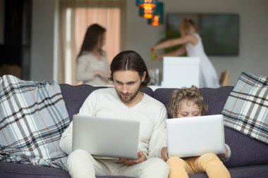 Baba ve oğul evde kanepede otururken dizüstü bilgisayarlar kullanarak