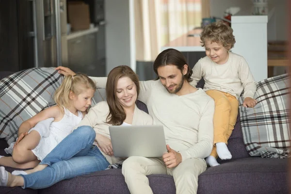 Famille heureuse avec des enfants utilisant un ordinateur portable sur le canapé à la maison — Photo