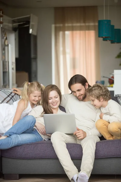 Семья с детьми, весело использующая ноутбук на диване, вертикальный — стоковое фото