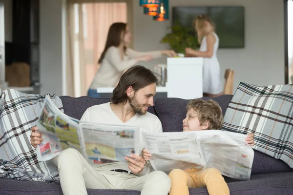 Feliz padre e hijo pequeño leyendo periódicos juntos en el sofá —  Fotos de Stock