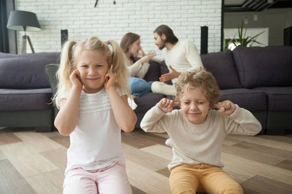 Children boy and girl covering ears, parents arguing at backgrou — Stock Photo, Image