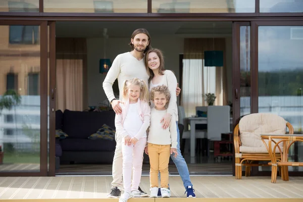 Family with kids looking at camera standing on house terrace — Stock Photo, Image