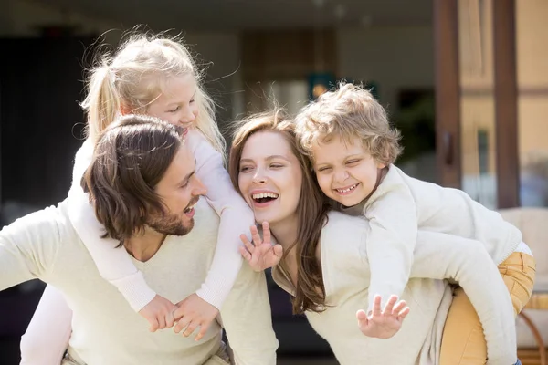 Szczęśliwy uśmiechający się rodzice piggybacking syn i Córka, leis dla rodzin z dziećmi — Zdjęcie stockowe