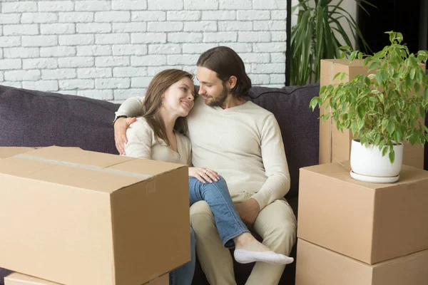 Молодая пара на диване переехала в новый дом с коробками — стоковое фото