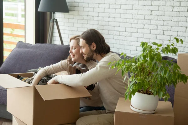 Young couple unpacking boxes sitting on sofa in living room