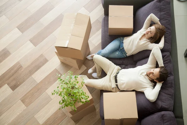 Relaxed couple resting on couch after moving in new home — Stock Photo, Image