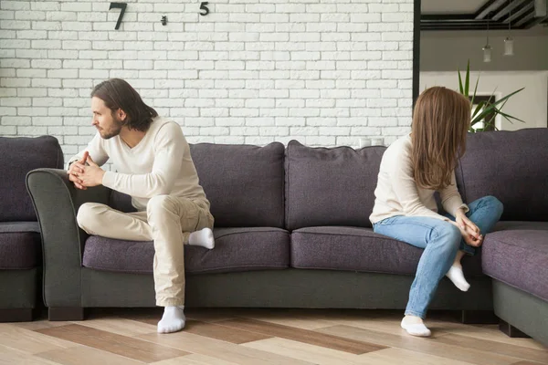 Unhappy sad couple sitting on couch after quarrel at home