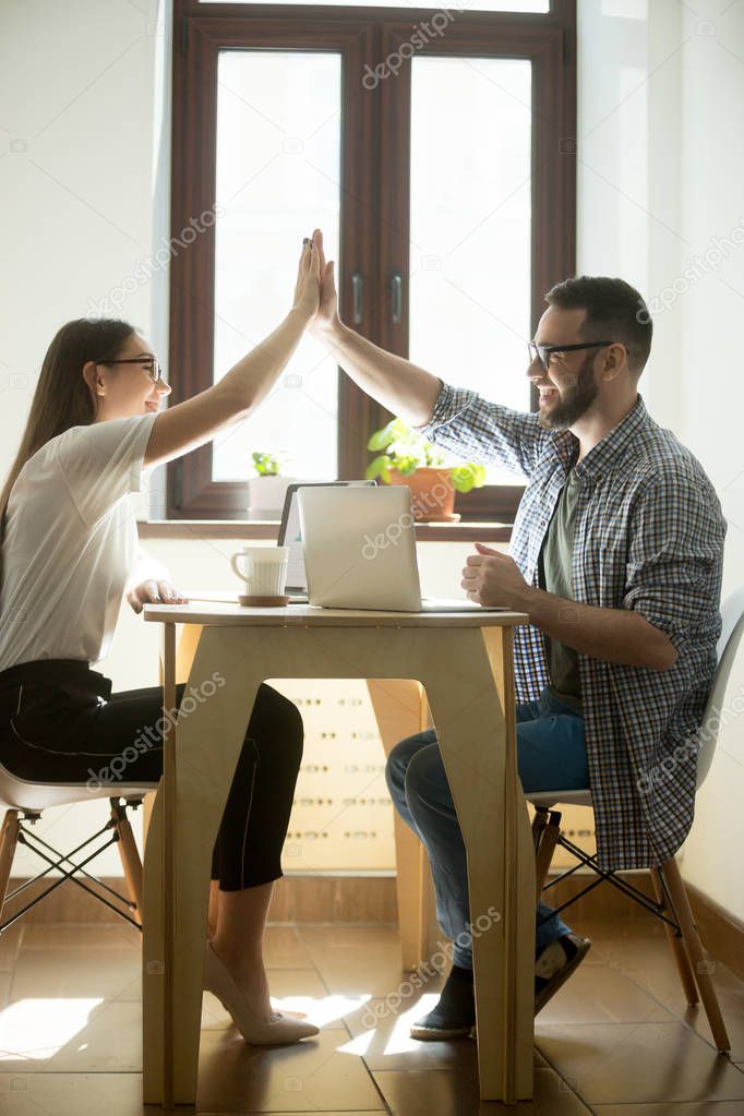 Two happy coworkers giving high fives on business meeting