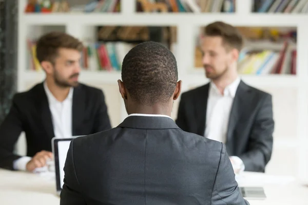 Rear view at african businessman sitting against two caucasian m — Stock Photo, Image