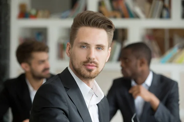 Young serious businessman looking at camera on meeting, headshot