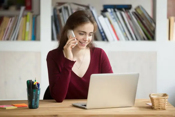 Lächelndes Mädchen mit Laptop, das am Schreibtisch sitzt und Anrufe entgegennimmt — Stockfoto