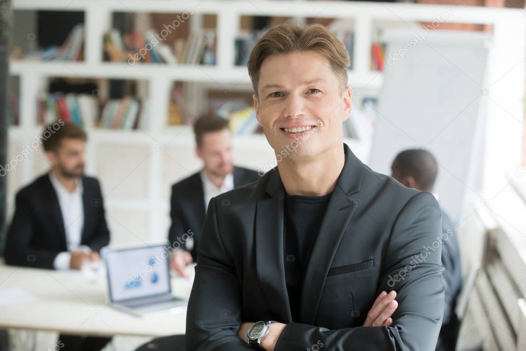 Smiling executive in suit standing arms crossed looking at camer