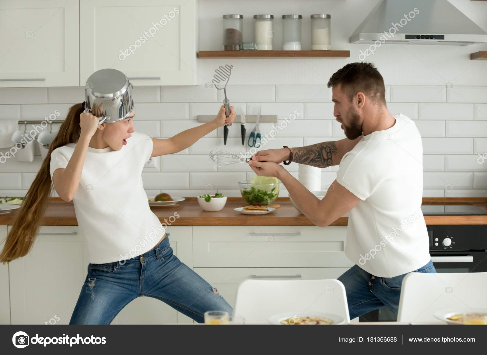  Funny  couple having fun fighting with kitchen  utensils 