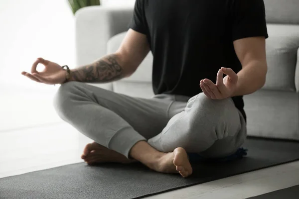 Sporty man with tattoo meditating practicing yoga in lotus pose — Stock Photo, Image