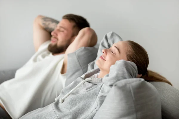 Relaxed young couple relaxing on comfortable sofa together at ho — Stock Photo, Image