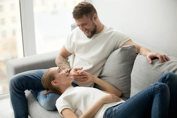 Affettuosa giovane coppia che si rilassa sul divano tenendosi per mano, divertente — Foto Stock