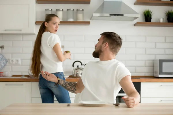 Angry husband and shocked wife arguing having conflict in kitche
