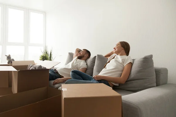 Mladý pár relaxační na gauči právě přestěhovala do nového domova — Stock fotografie
