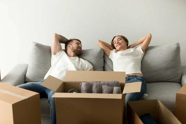 Молодая счастливая пара наслаждается удобным диваном, переезжающим в новый дом — стоковое фото