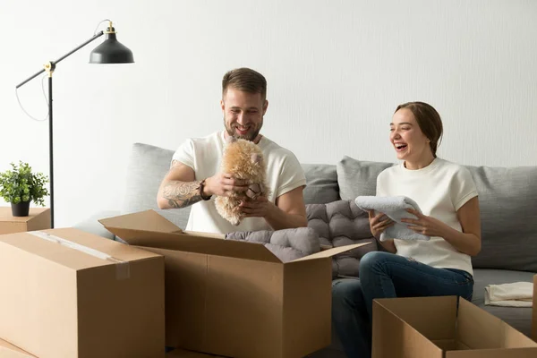 Riendo joven pareja tener divertido embalaje cajas en nuevo hogar — Foto de Stock