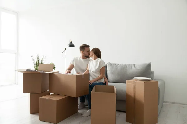 Coppia baciare seduta sul divano in soggiorno con scatole — Foto Stock