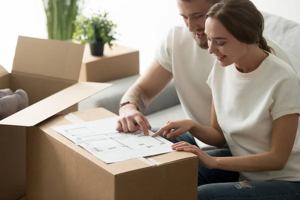 Happy young couple looking at blueprint planning new home design