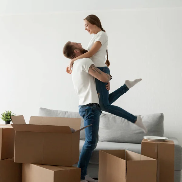 Hombre levantando mujer de pie entre cajas feliz de moverse en — Foto de Stock