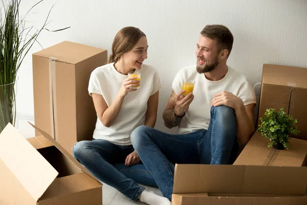 Smiling couple moved into new home having break drinking juice
