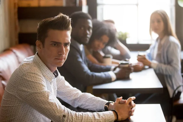 Diverse friends looking at frustrated man sitting alone in cafe — Stock Photo, Image