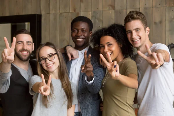 Happy multi-ethnic young people showing peace sign looking at ca — Stock Photo, Image