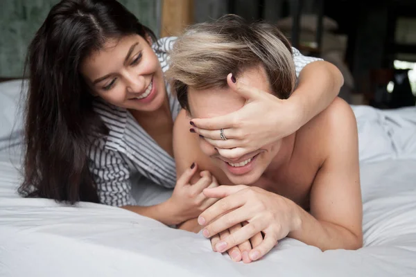 Couple jouant au lit, femme fermant les yeux de l'homme avec les mains — Photo