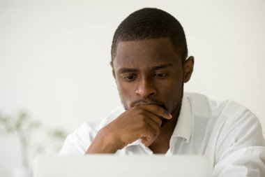 Focused african manager working on laptop thinking of problem so