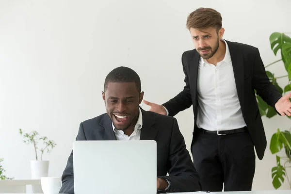 Angry boss catching african employee entertaining online instead
