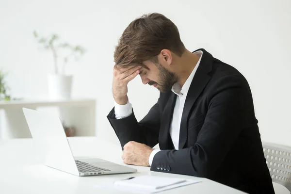 Depressed businessman shocked by bankruptcy failure sitting at w