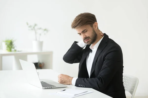 Jonge zakenman in pak gevoel van nekpijn na zittend werk — Stockfoto