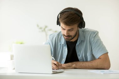 Odaklı Online zekâ öğrenme notlar yazma kulaklıklar giyen adam