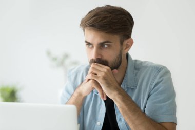 Dizüstü bilgisayar önünde düşüncelerinde kayıp düşünceli ciddi adam 