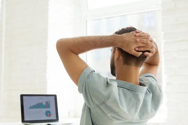 Vista trasera en el hombre mirando las estadísticas en la pantalla del ordenador portátil — Foto de Stock