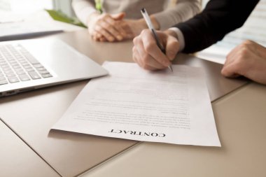 Çalışma masası dizüstü bilgisayar, tükenmez kalem ile finansal anlaşma metninin altında onun imzası kadın iş ortağı huzurunda koyarak işadamı ile yalan kağıt sözleşme belge görüntüsünü kapatmak