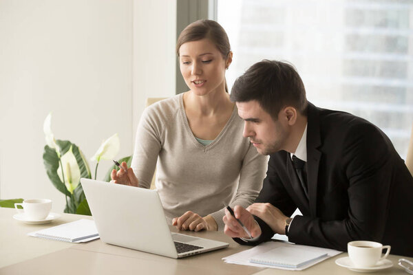 Young female employee showing calculations to boss