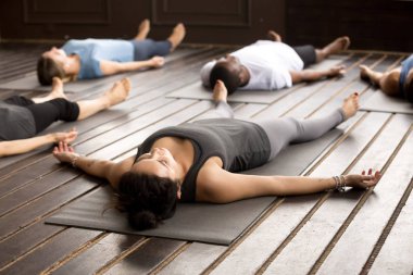 Group of sporty people in Savasana pose clipart