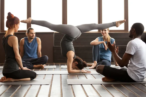 年轻运动妇女在 Pincha Mayurasana 姿势和小组 — 图库照片