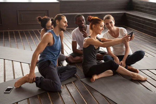 Smiling multiracial people making selfie on smartphone at yoga t